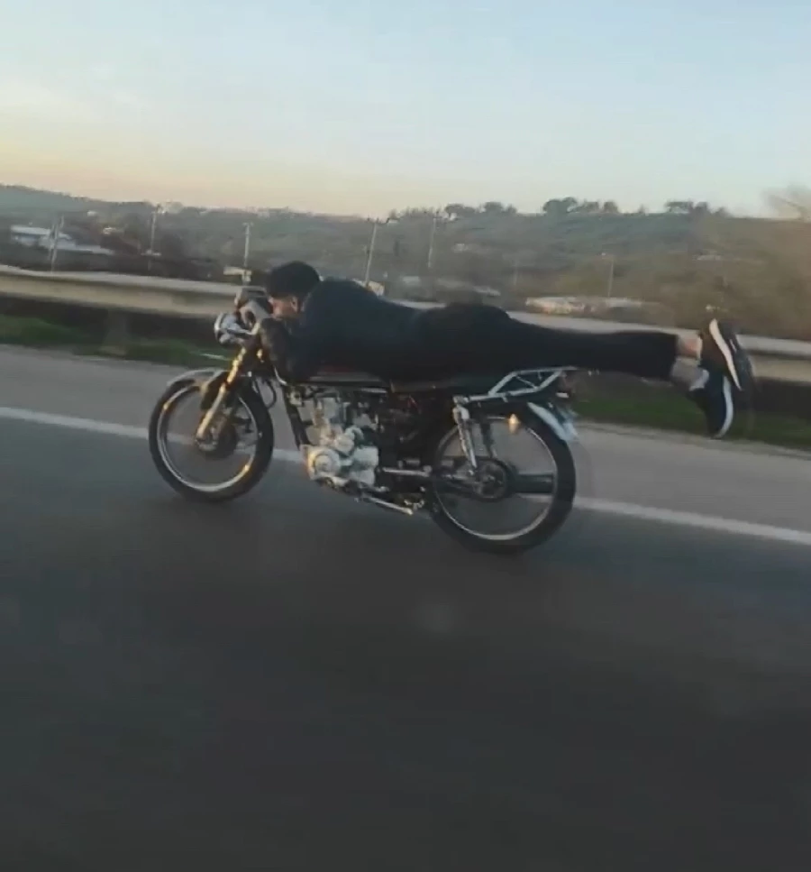 Kasksız sürücü motosikleti yüzüstü yatarak kullandı